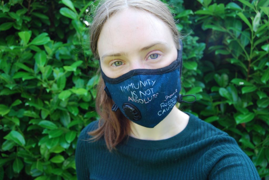A further photograph of Sakara wearing the mask and looking directly into the camera.