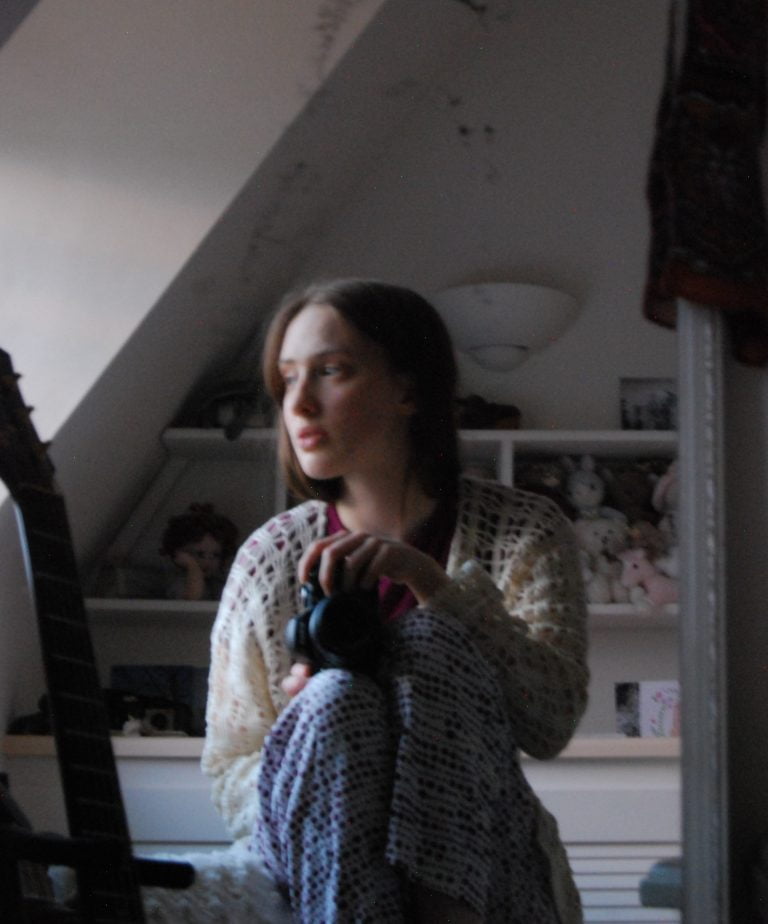 Photo taken in a mirror of a thoughtful looking white girl wearing pyjamas.