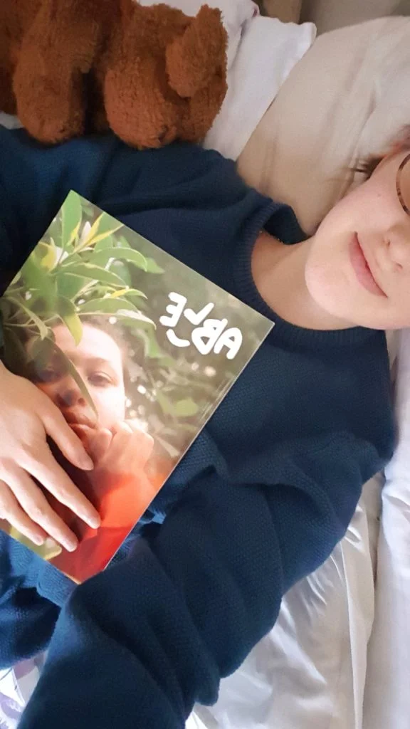 Sakara lays on her bed hugging a magazine to her chest.